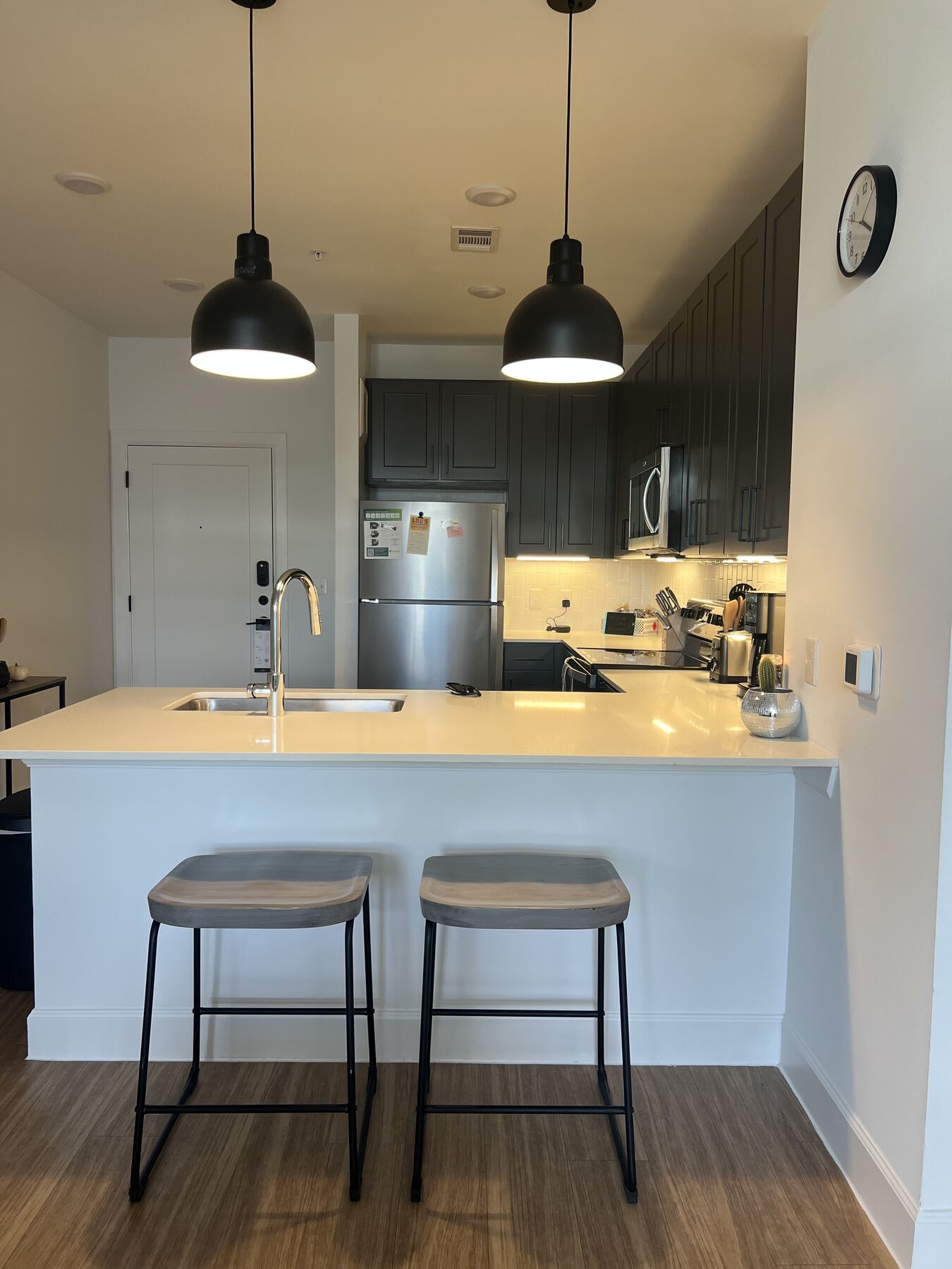Modern kitchen with dark cabinetry, white quartz counters, and black pendant lights